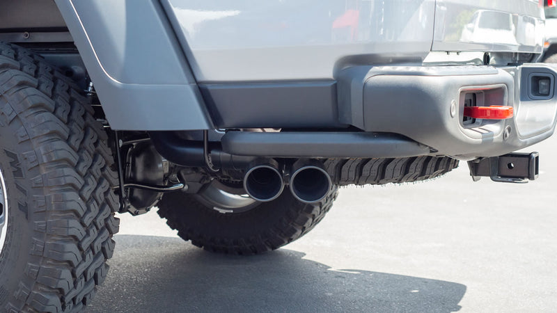 Borla Touring Cat-Back Exhaust System on a Jeep Gladiator: low rear view of a gray Jeep Gladiator showing dual black Borla tips exiting ahead of the rear bumper