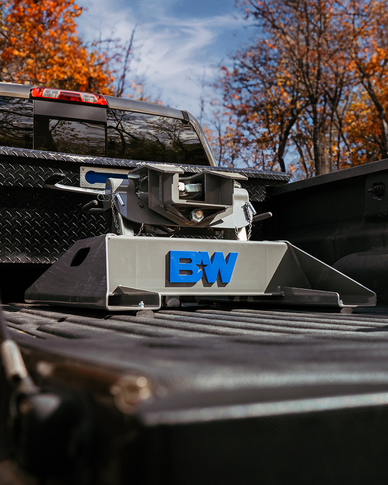 B&W Companion fifth wheel hitch installed in a pickup bed, low angle with autumn trees behind