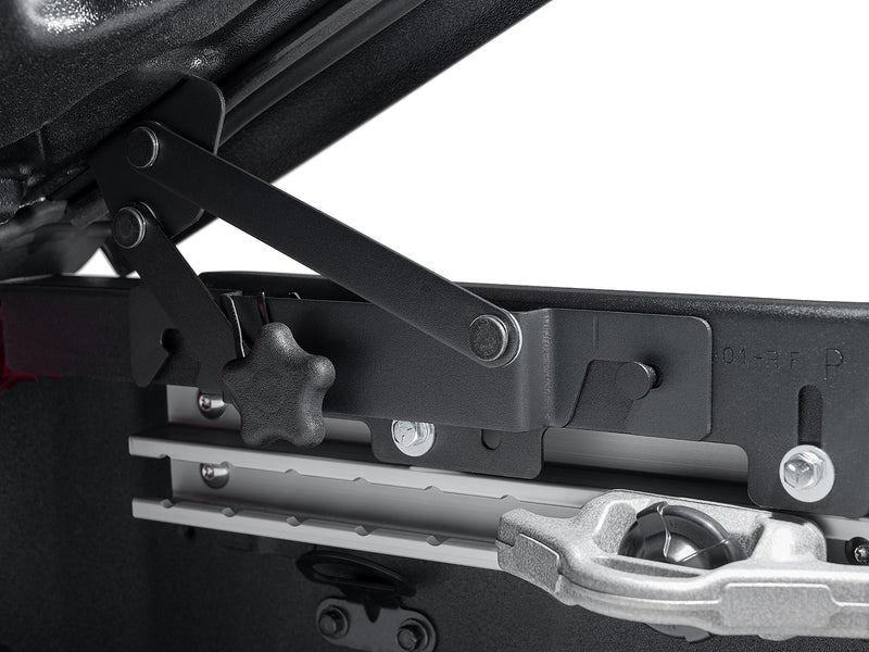 Close-up of the hinge linkage and its clamp knob where the Elite lid meets the aluminum mounting rail on the bed wall.