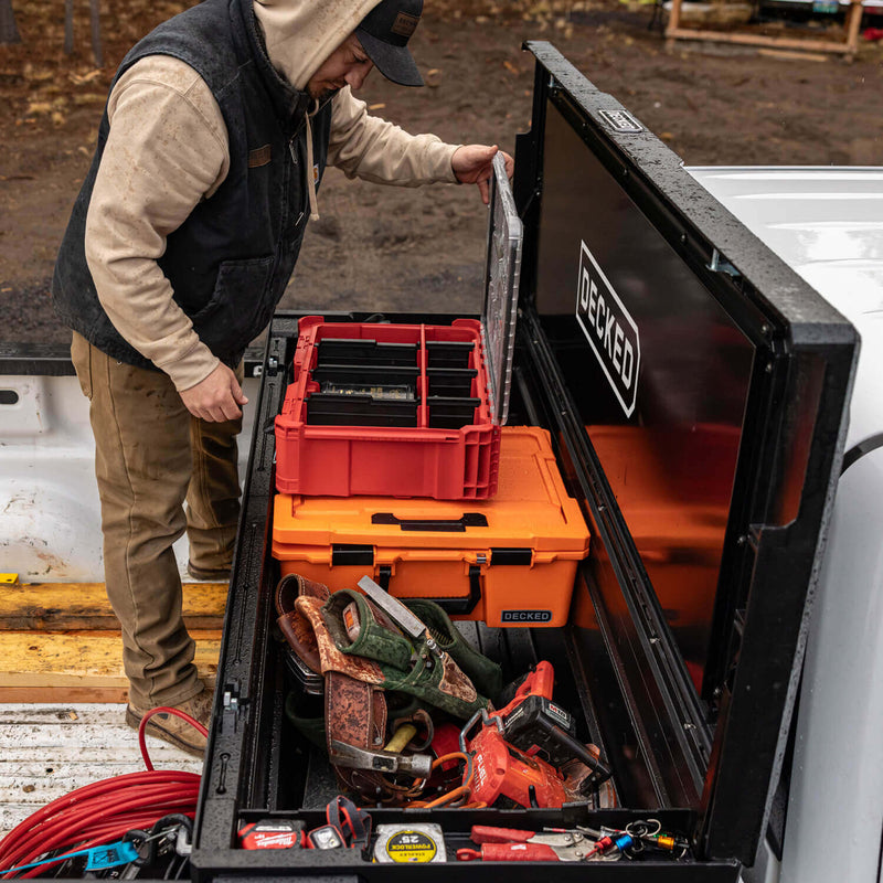 Black DECKED Tool Box open on a jobsite with DECKED D-co cases and hand tools organized inside the tub