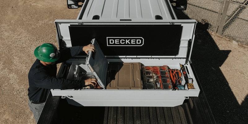 Overhead view of an open Industrial White DECKED Tool Box loaded with DECKED cases and small-parts organizers in a pickup bed