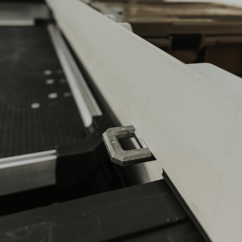 Close-up of the metal D-ring tie-down point on the side of an Industrial White DECKED Tool Box above a truck bed