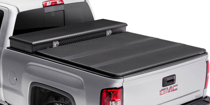 Hard folding tonneau cover closed behind a separate crossover toolbox, rear three-quarter studio view
