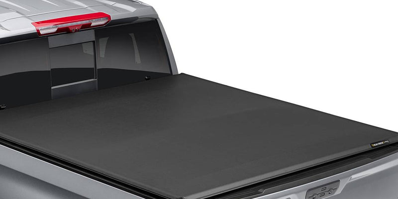 Soft folding tonneau cover closed flat over a silver pickup bed, rear three-quarter close-up