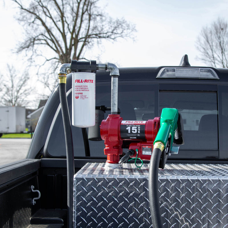 Fill-Rite FR1210HA1F 12V DC 15 GPM fuel transfer pump with filter and diesel nozzle, mounted on a diamond-plate transfer tank in a pickup bed