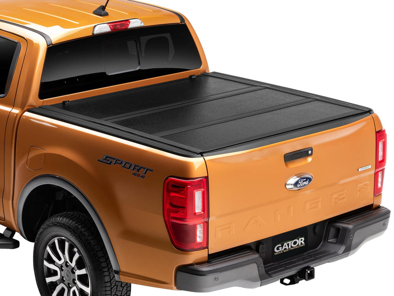 Gator EFX hard folding tonneau cover: Orange midsize pickup from the rear three-quarter with the black hard tri-fold cover closed