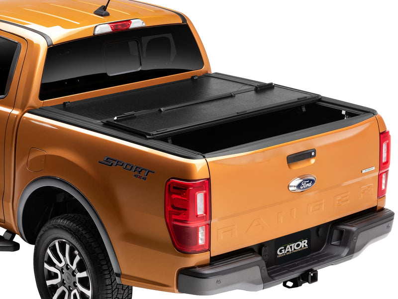 Gator EFX hard folding tonneau cover: Orange Ford Ranger from the rear three-quarter with the front section of the hard tri-fold cover folded