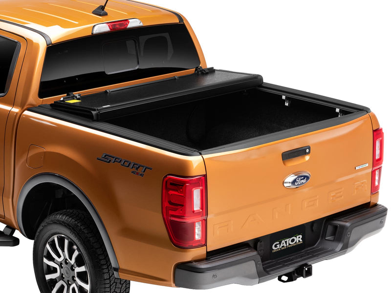 Gator EFX hard folding tonneau cover: Orange Ford Ranger from the rear three-quarter with the hard tri-fold cover partly folded