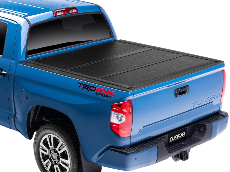 Gator EFX tonneau cover (closed) on a Toyota pickup: rear three-quarter view of a blue Toyota TRD 4x4 Sport with the black hard folding tonneau cover fully closed