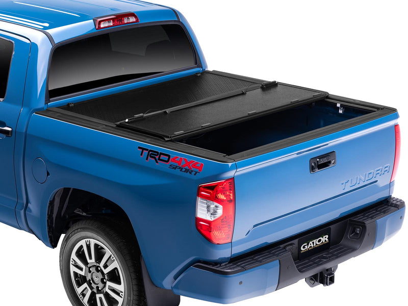 Gator EFX hard folding tonneau cover: Rear three-quarter view of a blue Toyota Tundra TRD 4x4 Sport with one panel of the hard folding cover folded forward