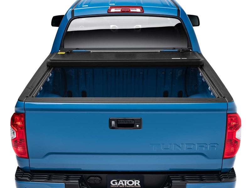 Gator EFX hard folding tonneau cover: Rear view of a blue Toyota Tundra with the hard folding cover folded fully toward the cab, bed open