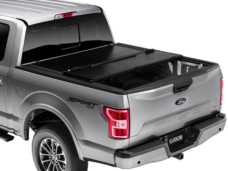 Gator EFX hard folding tonneau cover: Silver Ford F-150 from the rear three-quarter with the front section of the hard tri-fold cover folded