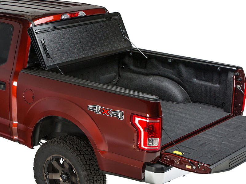 Gator FX hard folding tonneau cover: all panels folded and propped upright against the cab of a red Ford pickup