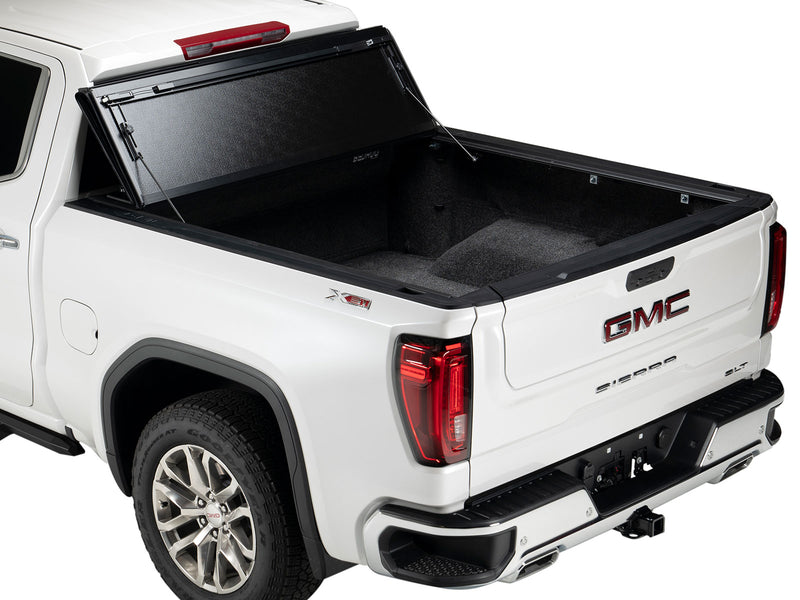Gator FX hard folding tonneau cover: all panels folded and propped upright against the cab of a white GMC pickup