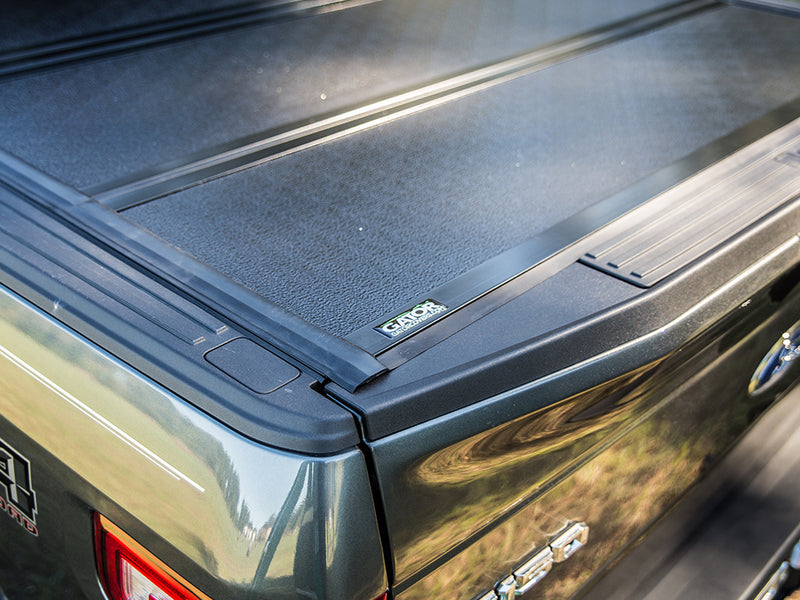Gator FX hard folding tonneau cover: close-up of the closed cover's rear corner and Gator badge on a dark green Ford pickup