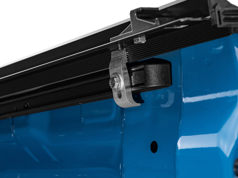 Gator SRX soft roll-up tonneau cover: Close-up of a soft roll-up tonneau side rail clamp under the rail of a blue truck bed