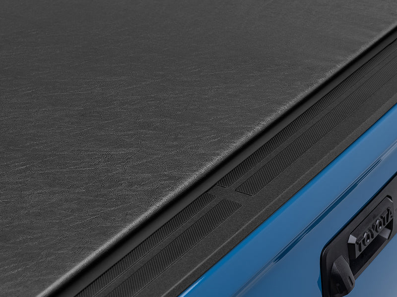 Gator SRX soft roll-up tonneau cover: Close-up of the closed black vinyl tonneau cover edge at the tailgate of a blue Toyota truck