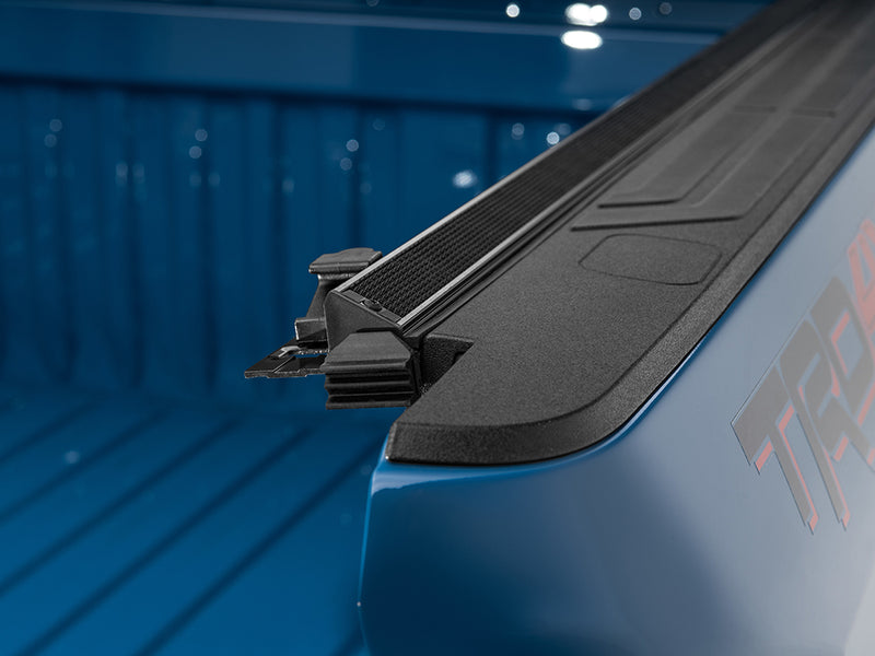 Gator SRX soft roll-up tonneau cover: Close-up of the soft roll-up tonneau rail end and tailgate seal on a blue truck bed with a TRD decal on the side