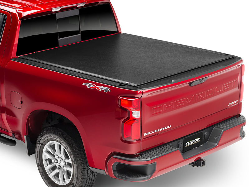 Gator SRX soft roll-up tonneau cover: Red Chevrolet Silverado 4x4 with a black soft roll-up tonneau cover closed over the bed, rear three-quarter view
