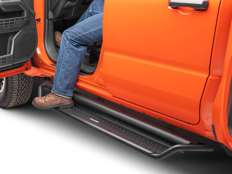 Go Rhino Dominator D1: person in jeans and work boots stepping onto a black side step under the open front door of an orange vehicle