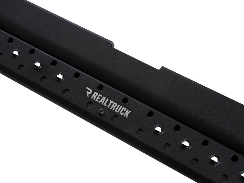 Go Rhino Dominator DSS: close-up of a black slider board showing the RealTruck badge plate and hex perforated holes