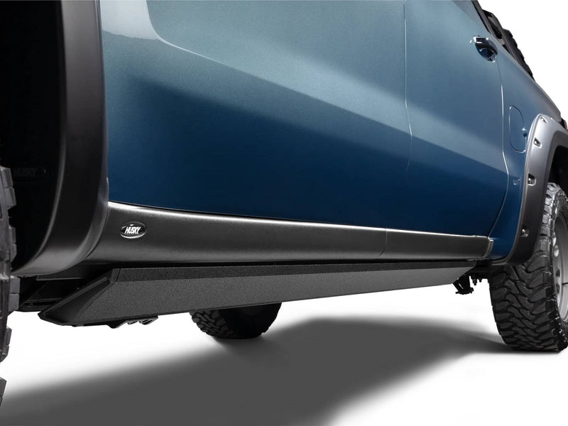 Bedliner-coated power running board tucked flush under the rocker of a blue pickup (bedliner finish)