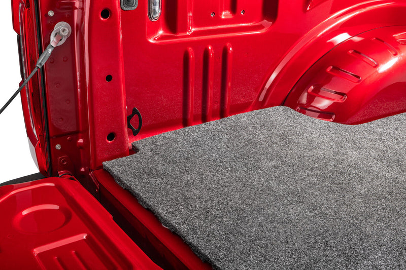 Husky Liners Guardian Comfort: close-up of a gray carpet bed mat corner at the tailgate opening of a red truck bed