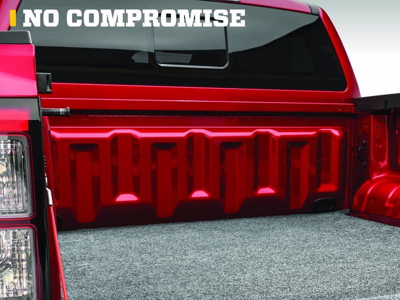Husky Liners Guardian Comfort: gray carpet bed mat on the floor of a red pickup bed, viewed past the tail lamp toward the cab