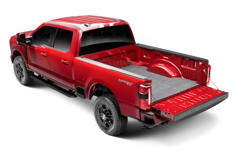 Husky Liners Guardian Comfort: red full-size crew-cab pickup with a gray carpet bed mat installed and the tailgate lowered, shown in a Ford F-250/F-350 Super Duty bed