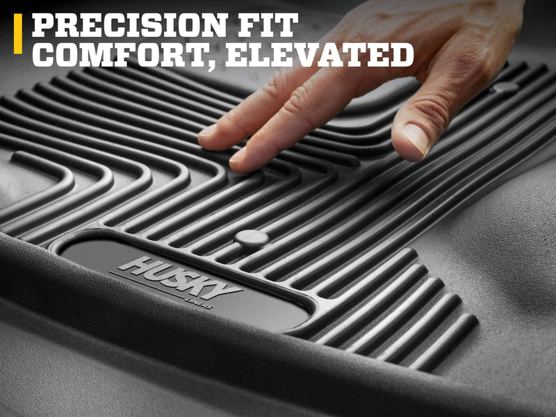 Husky Liners X-act Contour: hand pressing on the ribbed surface of a black Husky floor liner