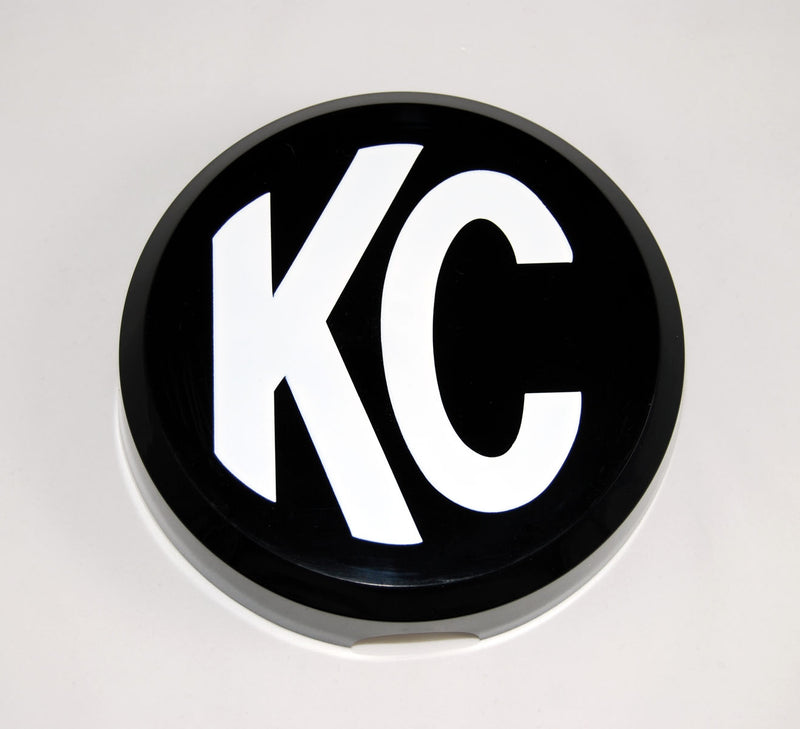 KC HiLiTES 6" Round Light Cover & Shield on a studio background: round black hard plastic light cover with a white KC logo on a light gray background