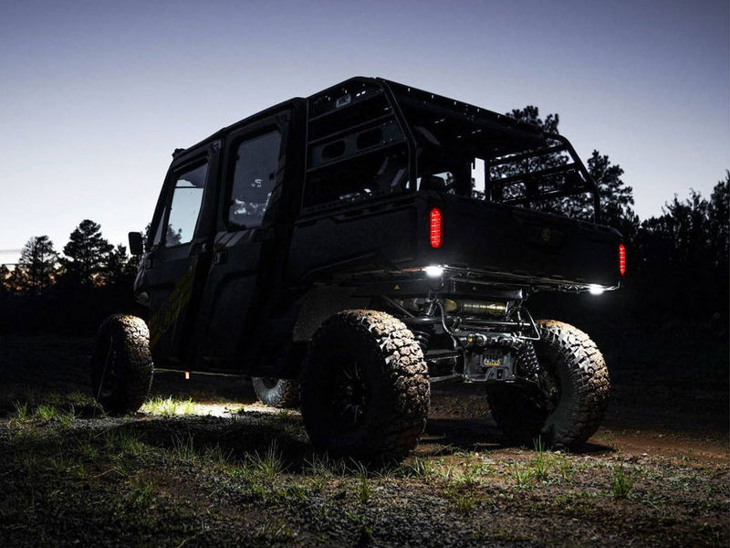 KC HiLiTES Cyclone V2 LED Rock Light 6-Light System on a vehicle: black UTV at dusk with white rock lights glowing under the cargo bed and rocker panel