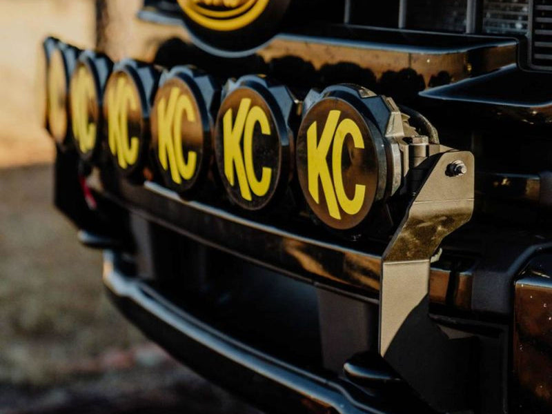 KC HiLiTES Gravity Pro6 45" 7-Light Front Bumper LED Light Bar Kit on a Ford Super Duty: close-up of a row of round KC lights with black and yellow KC covers mounted on a black bracket across a truck front bumper