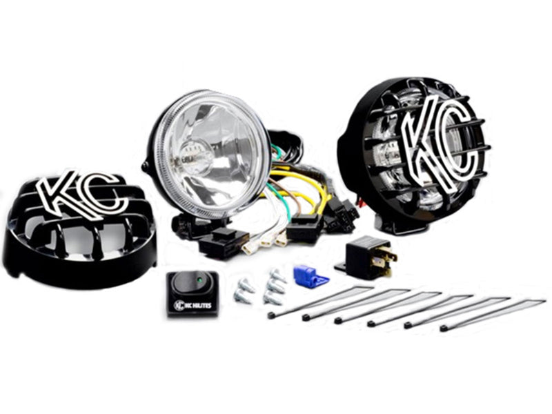 KC HiLiTES Rally 400 4" Halogen Light on a studio background: two 4" round halogen lights with KC stone guards, wiring harness, rocker switch, relay, screws and cable ties