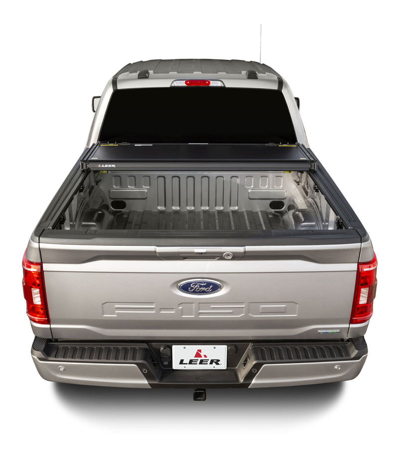 LEER HF350M hard folding tonneau cover on a pickup bed: rear view of a hard folding cover folded fully against the cab, open bed exposed
