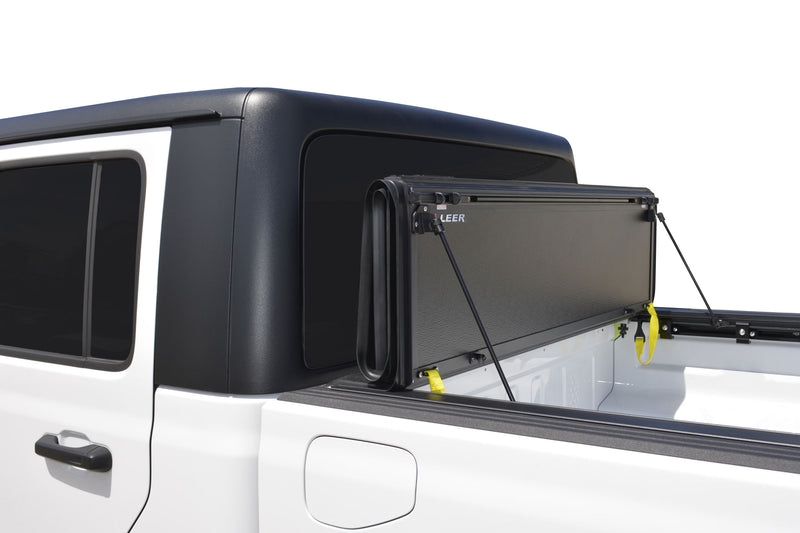Close-up of the LEER HF650M hard folding tonneau cover: close view of a hard folding cover folded upright behind the cab, held by prop rods