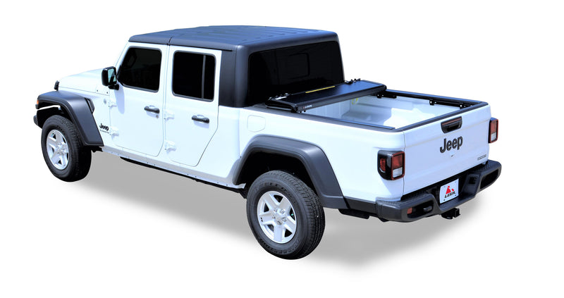 LEER HF650M hard folding tonneau cover on a pickup bed: hard folding cover folded into a stack at the front of a white pickup bed, bed open (tow hitch accessory shown, not included)
