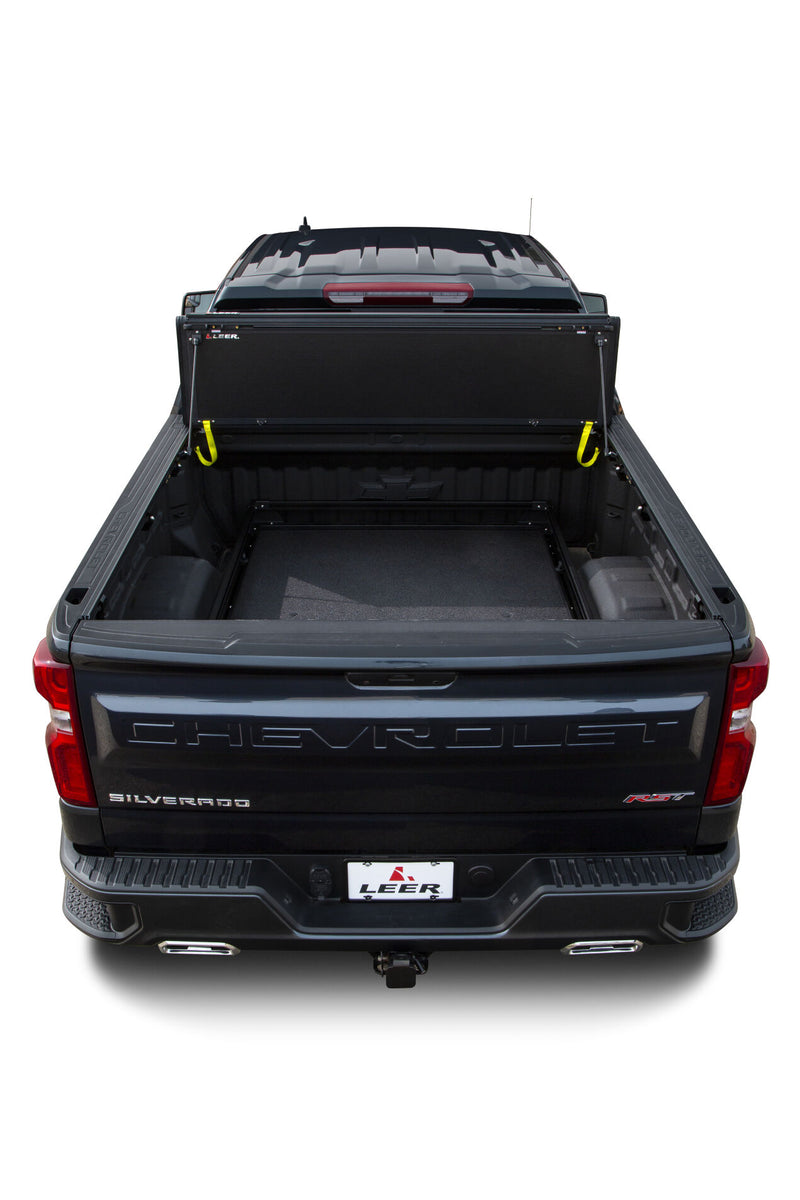 LEER HF650M hard folding tonneau cover on a pickup bed: overhead rear view of a hard folding cover stood up against the cab, open bed exposed (bed slide shown, not included)
