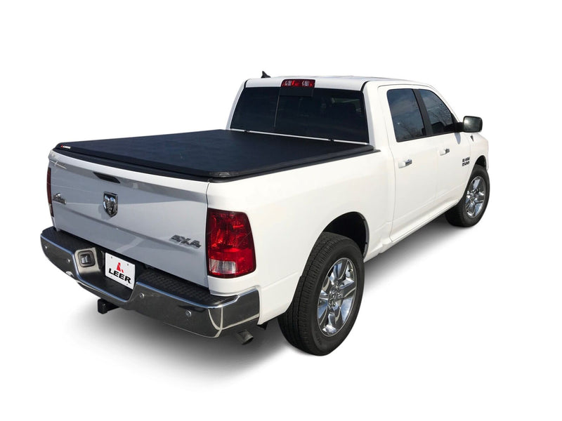 LEER Latitude soft folding tonneau cover on a pickup bed: black soft folding tonneau cover closed flat over a white pickup bed, rear three-quarter view