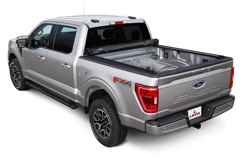 LEER SR250 soft roll-up tonneau cover on a pickup bed: silver pickup with a black roll-up cover fully rolled against the cab, open empty bed