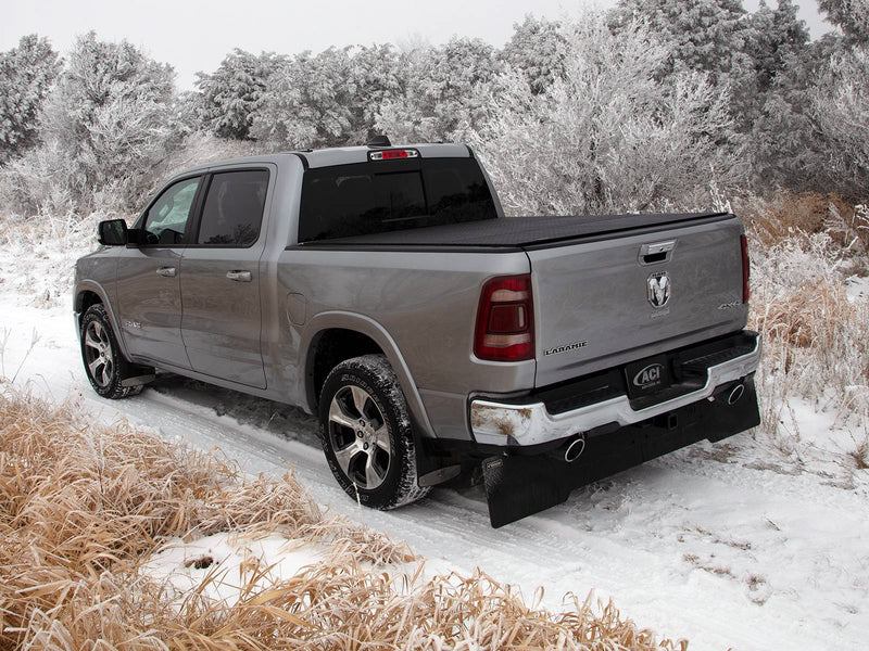 Silver pickup in snow and frosted brush with a black hard tonneau cover closed