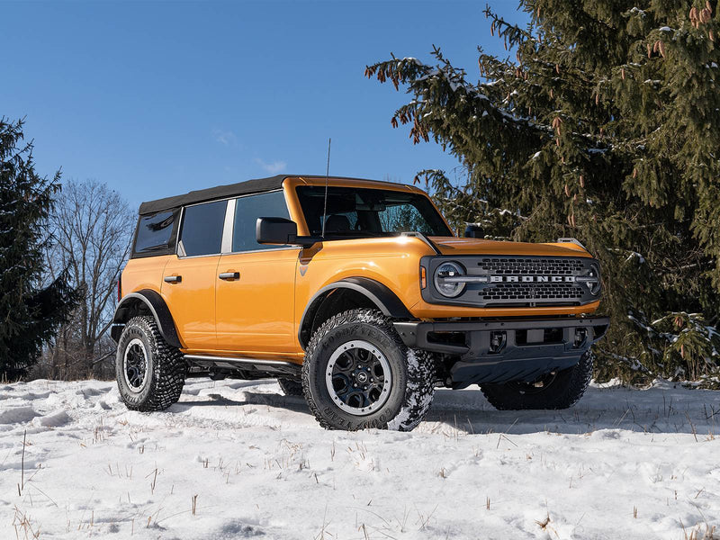 N-Fab TrailSlider step system in textured black, front three-quarter view, installed along the rocker in snow, on a Ford Bronco