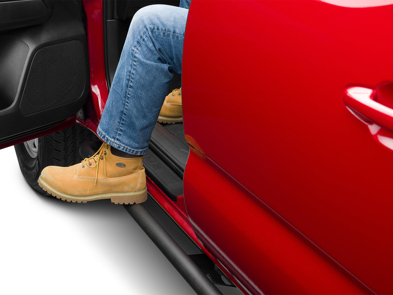 N-Fab TrailSlider step system in textured black, boot on the step at an open door, on a Toyota Tacoma