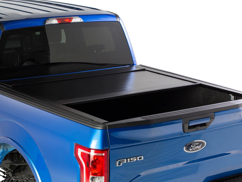 Pace Edwards BedLocker: blue pickup with the black retractable cover partly open over the rear of the bed