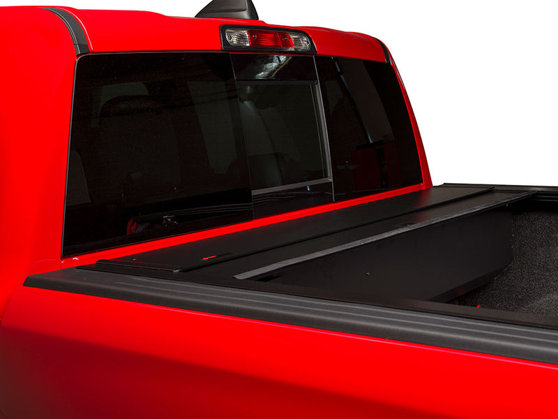 Pace Edwards BedLocker: red pickup cab with the cover retracted into the front canister, carpet-lined bed exposed