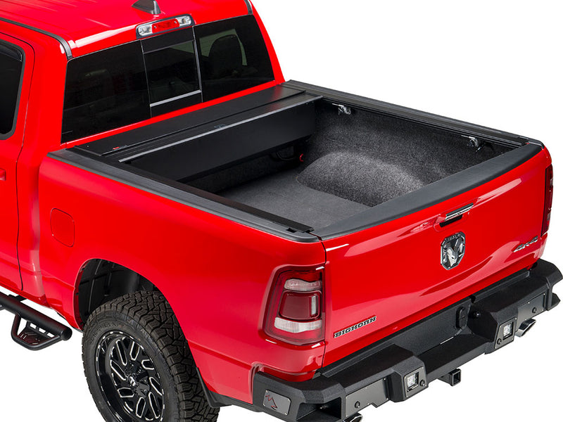 Pace Edwards BedLocker: retractable cover fully open on a red pickup, canister at the front of a carpet-lined bed