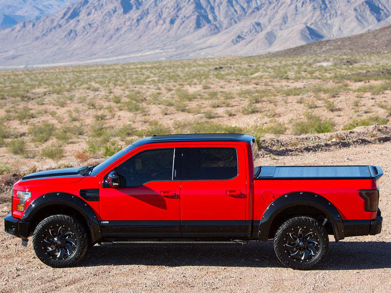 Pace Edwards BedLocker: side profile of a red pickup with a black retractable cover closed, desert mountains behind
