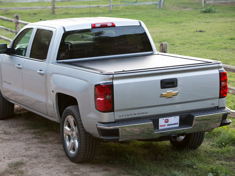 Pace Edwards JackRabbit: black retractable cover fully closed on a silver pickup bed beside a wooden fence