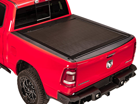 Pace Edwards JackRabbit: black retractable cover fully closed on a red pickup bed, white studio background
