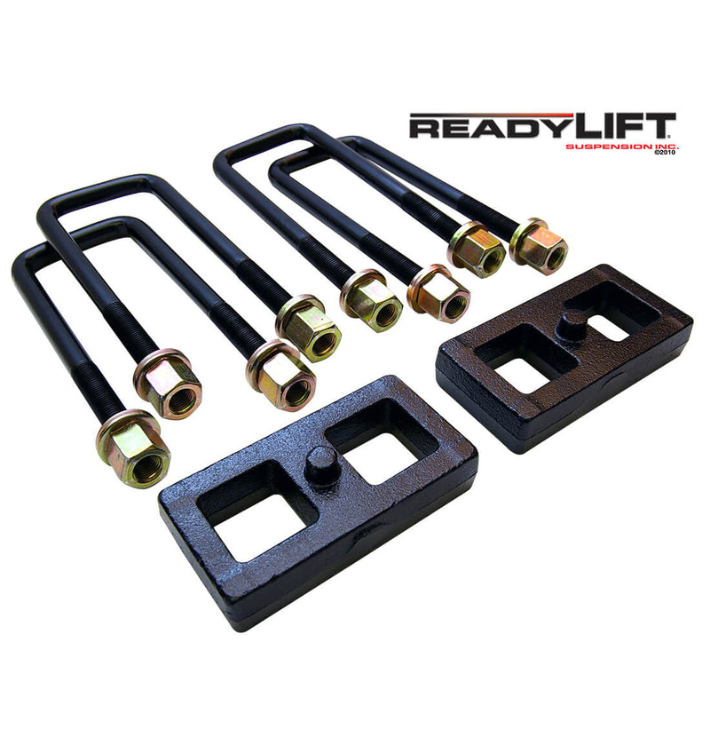 ReadyLIFT Block Kit, full kit on a studio background: two flat black cast 1" rear lift blocks with four square U-bolts and gold nuts beside a ReadyLIFT logo